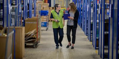 two older women walking together in a warehouse