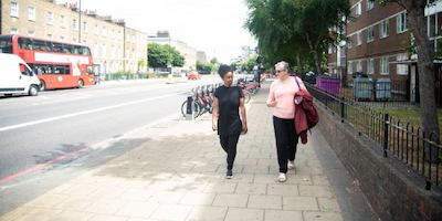 two older women walking together on a sunny street