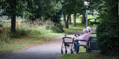 two older people sat on a bench outside