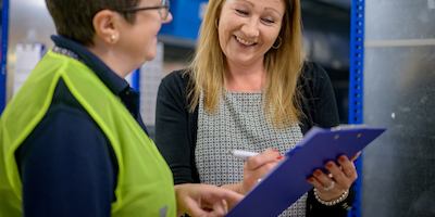 two older women writing on a clip board and talking