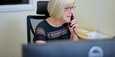 Image of a woman at a laptop on the phone