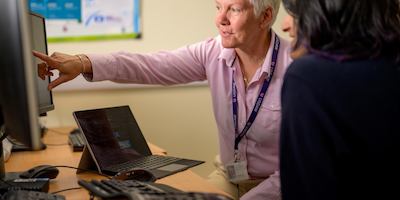 Two office workers working at a computer screen