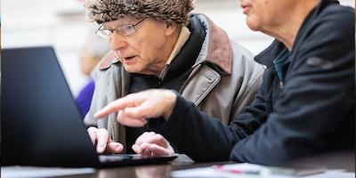 Two older men looking at a laptop