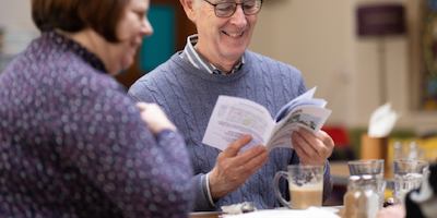 An older man chatting with a woman reading a book