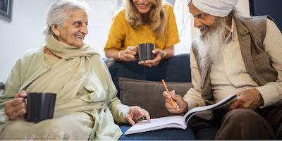 An older group of people sitting on a sofa and chatting