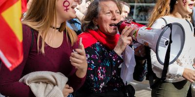 Three women with flags and megaphones at a protest