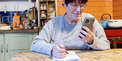 Older woman using phone in kitchen