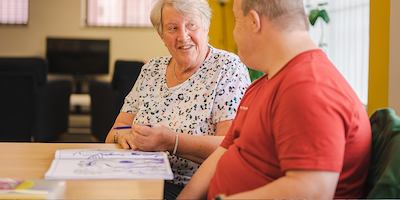 Two older people sitting down and chatting