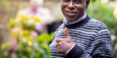 Man in a garden smiling giving a thumbs up at the camera