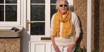 Older woman standing outside her door