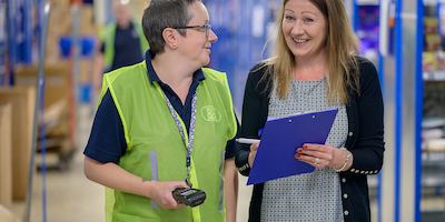Two older women working with a clipboard