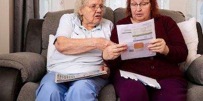 Two older women reading bills