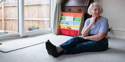 Older woman sitting on floor in her home