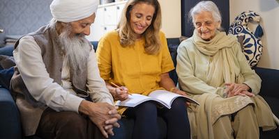 A Sikh family sitting on their sofa making planning notes in a notebook