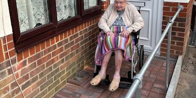 An-older-woman-in-a-wheelchair-in-front-of-her-house
