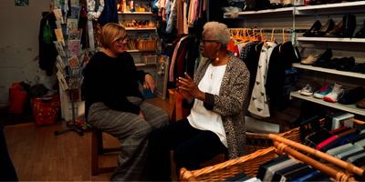 Two older women chat in a charity shop