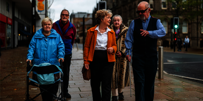 A group of older people walk down a street