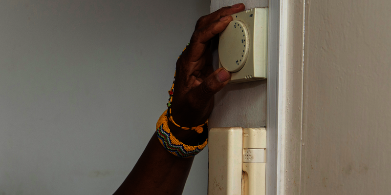 A person turning up a thermostat