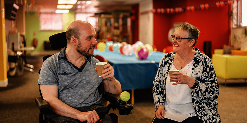 Two older people sharing drinks in a care home