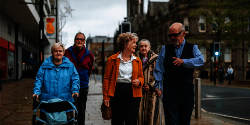 A group of older people walk down a street