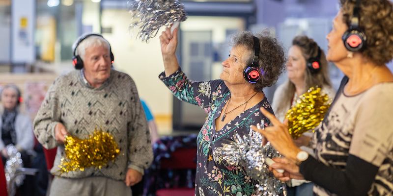 People dancing at silent disco with tinsel pompoms 