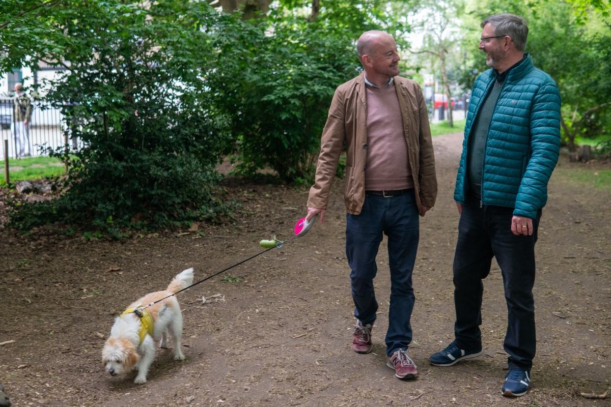 Michael and his husband Johnny walking in the woods with their dog