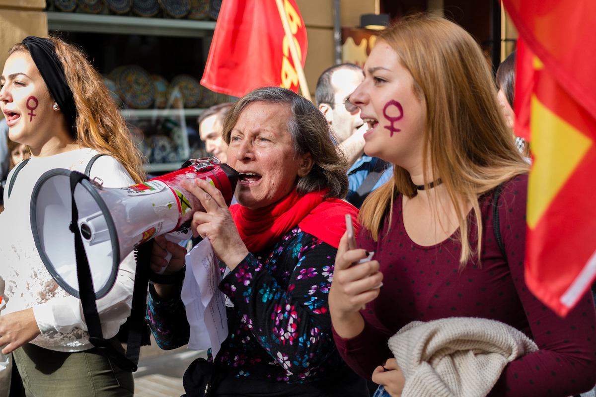 Three women with flags and megaphones at a protest