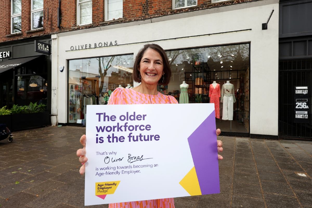 A woman standing outside of Oliver Bonas with an Employer-pledge sign