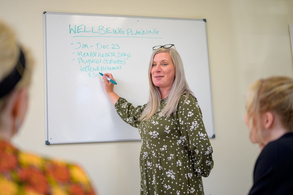 Person showing other people writing on a whiteboard