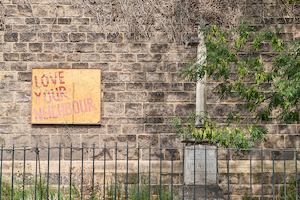 Brick wall with 'love your neighbour' sign.