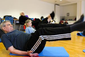 Pupils in a physio yogalates class doing a balancing rocking pose.