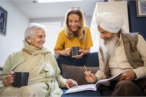 An older group of people sitting on a sofa and chatting