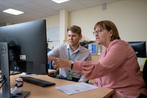 Two workers talking in front of a desktop