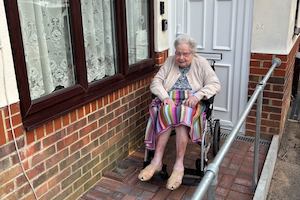 An-older-woman-in-a-wheelchair-in-front-of-her-house