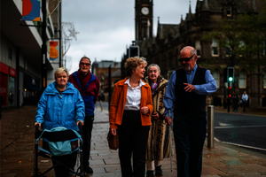 A group of older people walk down a street