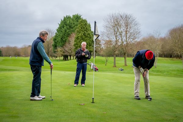 Three older men playing golf