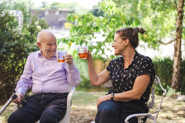 older woman and her father sitting outside together drinking tea