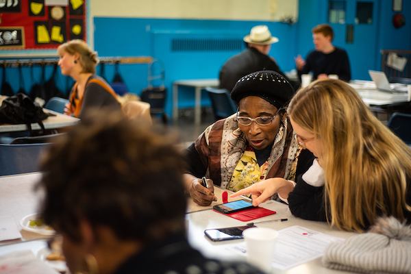 Older and younger person using phone at South London Cares workshop