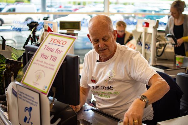 Man working at Tesco till.