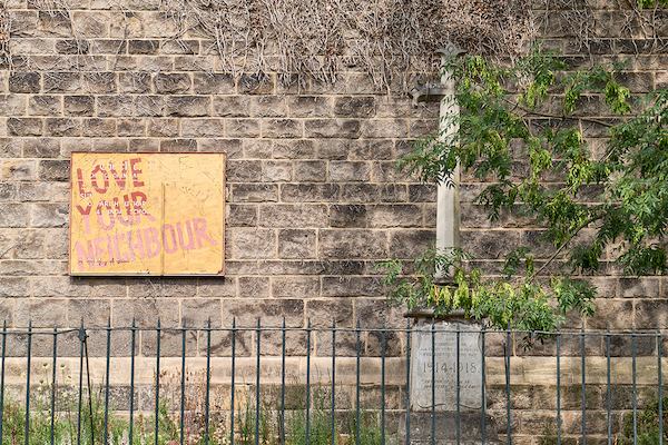 Brick wall with 'love your neighbour' sign.