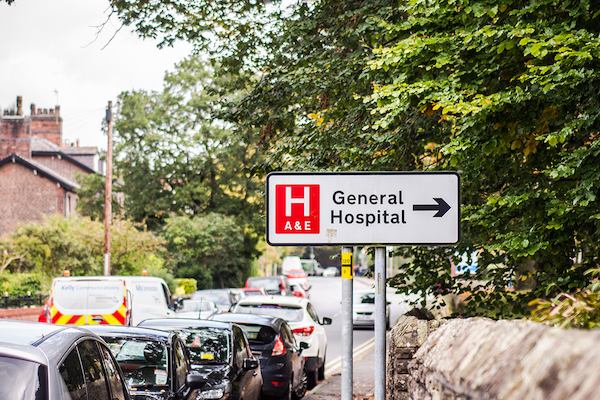 This photo is taken on the street outside of a hospital with sign saying 'General Hospital'.
