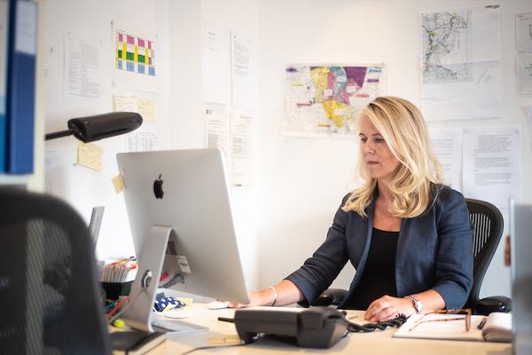 Middle aged woman seated at desk in office.