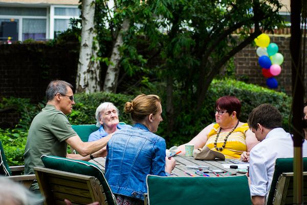 Small group of young and old people sitting at a table on a summer day.