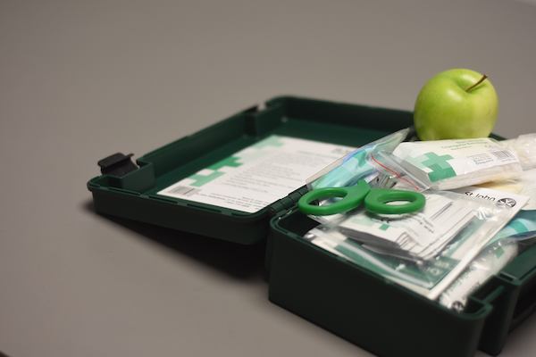 Open first aid kit with a green apple in it.