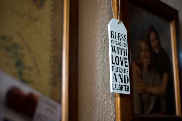 'Bless this house with love, friends and laughter' tag hanging from a family photo.