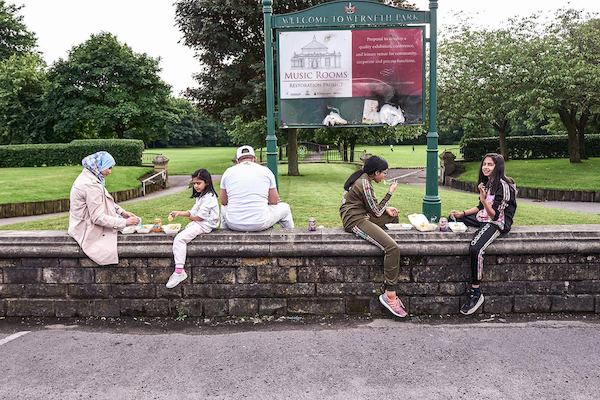 Family group sitting on a wall in a park