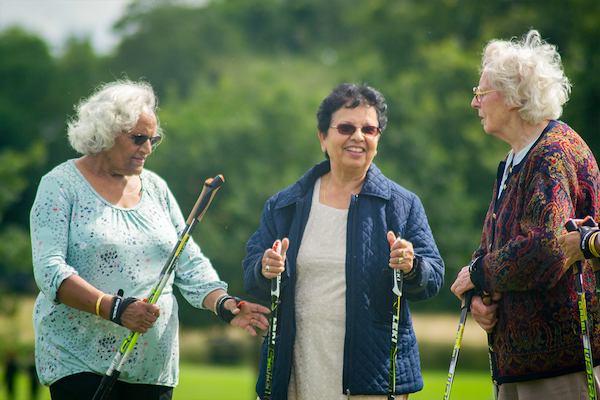 Three elderly women with nordic walking sticks.