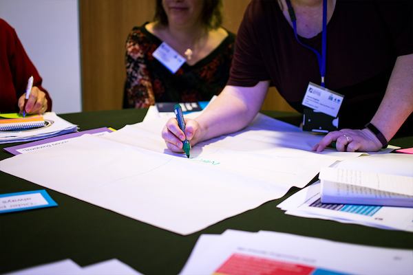People brainstorming with pens and paper at a conference.