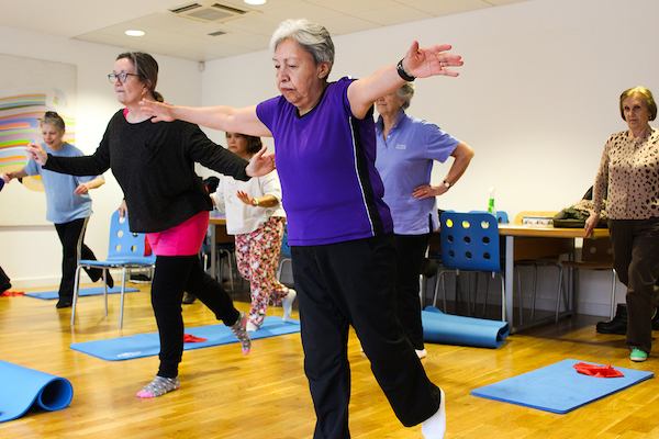 Women in physio yogalates class doing a balancing pose.