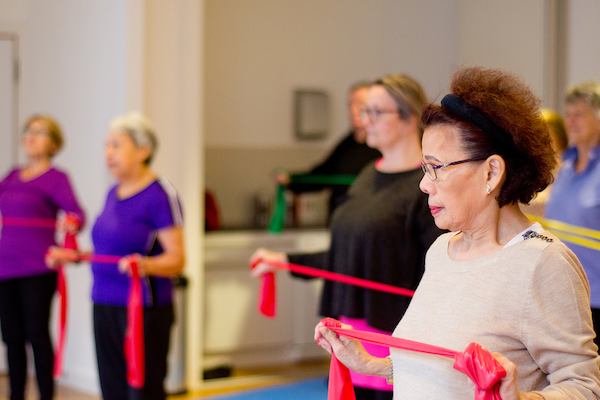 Older Asian woman using resistance band